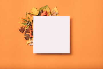 White blank paper. Holiday greeting. Autumn leaves decor. Orange background.