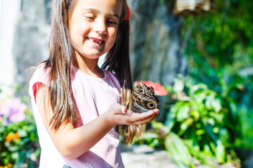 Little girl holding a butterfly in a field