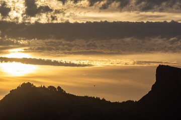 View of Sierra Elvira in Granada at sunset with the sun between the clouds and the silhouette of a house on top of the hill