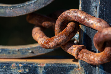 Detail of the links of a rusty chain on a corroded iron door