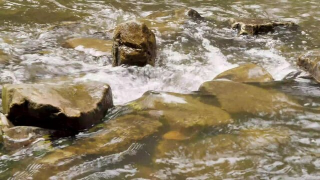 Close up of rocks in a fast flowing river after heavy rain