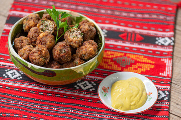 fried meat balls in clay bowl on traditional cloth