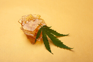 high thc, pieces of yellow cannabis wax and green leaf, marijuana concentrate