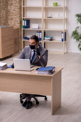 Young male employee in the office during pandemic disease