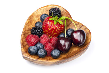 Fresh different berries in wooden bowl in the shape of heart isolated on white background. Full depth of field with clipping path.