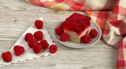 Piece of raspberry cake on with plate, raspberies fruits, wooden plate close up
