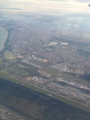 Aerial panoramic view of city with airplane wing and clouds