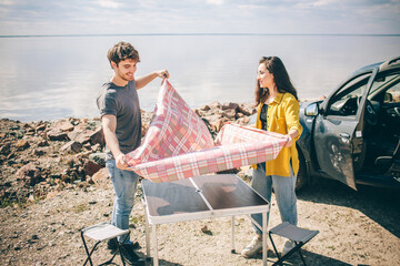 Picnic near the water. Happy family on a road trip in their car. Man and woman are traveling by the sea or the ocean or the river. Summer ride by automobile.