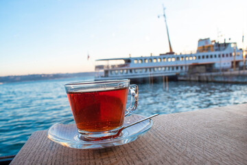 A cup of Turkish tea against the background of the cruise ship. Turkish tea served in the typical manner. Turkish tea in mug cup. Bosphorus