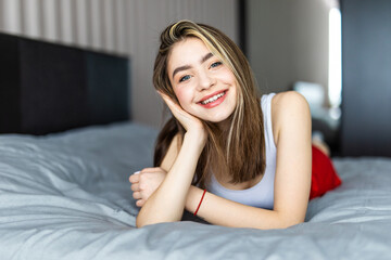Pure beauty. Beautiful young woman looking at camera while lying on the bed at home