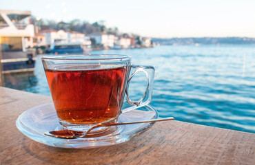 A cup of Turkish tea against the background of the cruise ship. Turkish tea served in the typical manner. Turkish tea in mug cup. Bosphorus