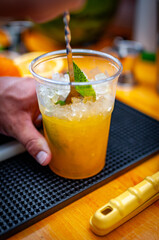 Cocktail preparation with orange, mint, maracuja and ice.