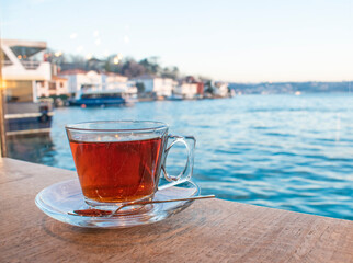 A cup of Turkish tea against the background of the cruise ship. Turkish tea served in the typical manner. Turkish tea in mug cup. Bosphorus