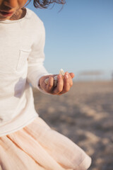 Little cute girl searching seashells on the sea beach