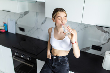 Gorgeous young woman drinking a glass of water in her kitchen
