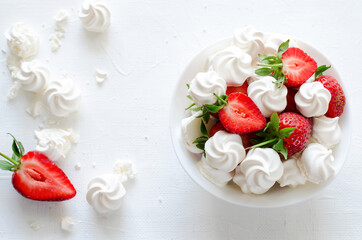 Fresh strawberries and meringues on white background
