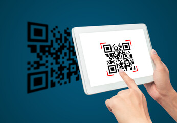 Hand using tablet computer scan Qr code on blue background. Cashless technology and digital money...