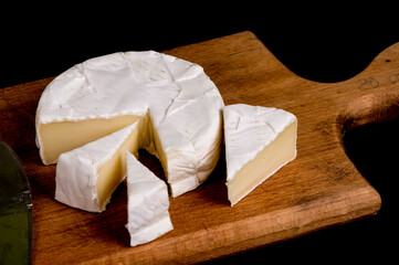 pieces of soft cheese Camembert on dark blackbackground. Delicious pieces of white mold cheeses with soft textures Camembert close up, macro