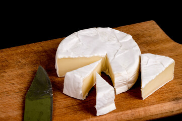 pieces of soft cheese Camembert on dark blackbackground. Delicious pieces of white mold cheeses...
