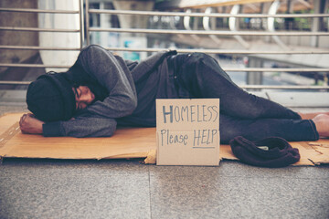 Homeless people poverty beggar man asking for money job and hoping help in helpless dirty city sitting with sign of cardboard box said "Homeless Please Help" on board. Beggar in city concept.