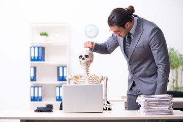 Young male employee and skeleton in the office