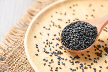 Black sesame seeds on wood spoon.