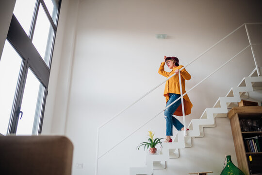 Adult woman going downstairs at home - Lovely woman cheerful on staircase