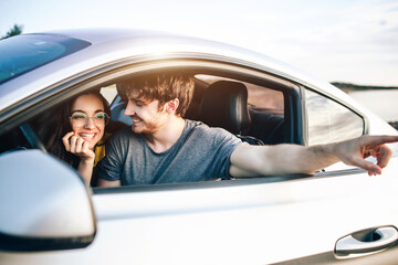 Trendy young women and man traveling by car. Relaxed happy couple on summer roadtrip travel vacation