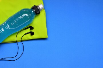 Isotonic drink and audio set on blue background, space for text, moments to do sports