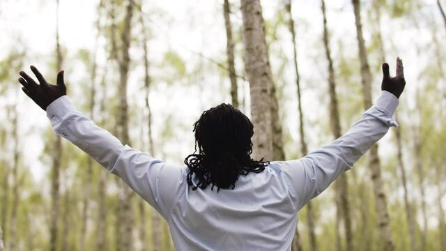 Black lives metters. African businessman with outstretche hands praying in the park.