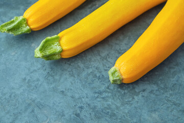 Three yellow zucchini on kitchen table. Whole raw courgettes