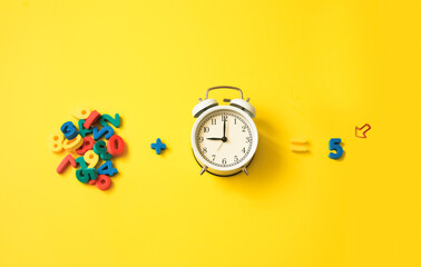 numbers and alarm clock on a yellow colorful background. Teaching and education, teaching children math