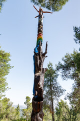 A standing wooden pillar with various figures carved on it in the Totem park in the forest near the...
