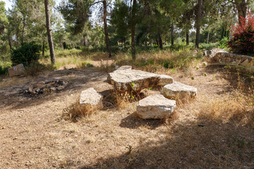 Large stones located like a table and stools in the Totem park in the forest near the villages of Har Adar and Abu Ghosh