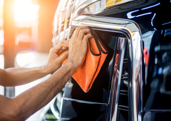 Car service worker polishing car with microfiber cloth.
