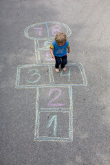 Child, blond boy, playing hopscotch on the street