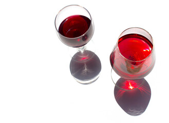 two glassed of red wine on white background with sparkling shadows. Free copy space.  Concept of organic drinks. Top view.