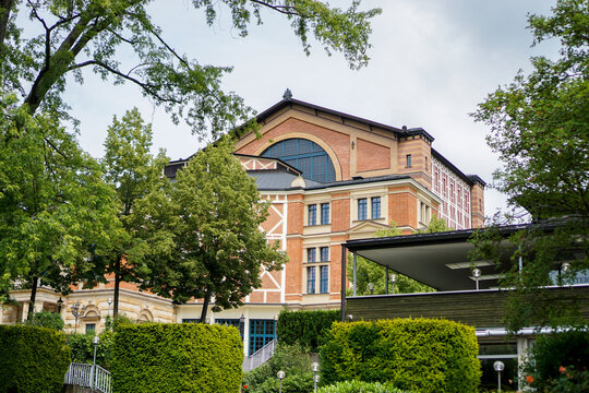 Sicht auf die Vorderansicht des Wagner Festspielhaus Bayreuth aus der Sicht des Parks. Bäume und Halle im Bild, blauer bewölkter Himmel.  Bayern, Deutschland.