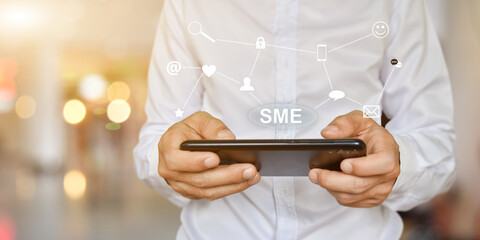 Businessman hand pressing button SME icon on virtual screen. Idea for Small and medium-sized...