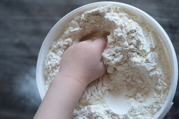 children's hand holds a handful of flour
