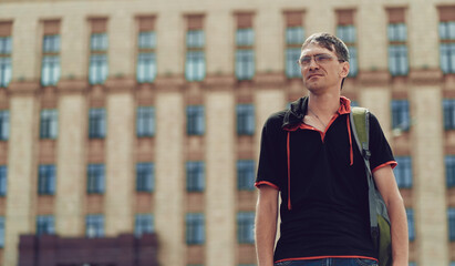 Man standing in yard of city. Portrait of young man in casual clothes standing.