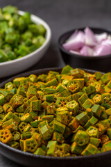 chopped raw okra mixed with turmeric powder in a bowl, preparation for indian vegetable bhindi fry