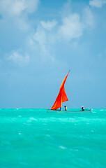 Sail boats in the lagoon of Rodrigues island. Traditional pirogues with bright orange sails