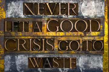 Never let a good Crisis go to Waste text formed with real authentic typeset letters on vintage textured silver grunge copper and gold background