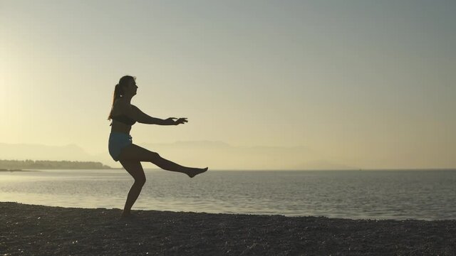 Beautiful girl doing fuette on the beach. Sea, sunrise, beach, woman.