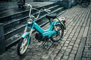 A vintage moped locked up on a cobbled street