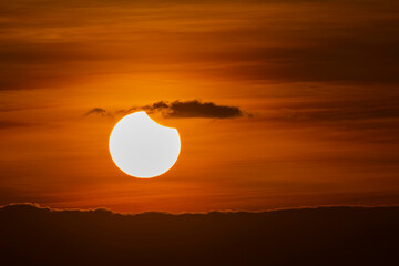 Beautiful moment of the sun eclipse during sunrise over the thick clouds.