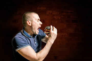 A hungry Man enjoys eating a black Burger.