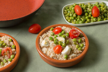 Cauliflower rice with peas, cherry tomatoes and quail eggs in a bowl.