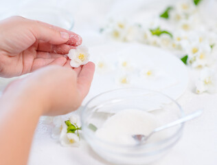 Obraz na płótnie Canvas Cook's hands cover jasmine flowers with sugar to decorate sweeties